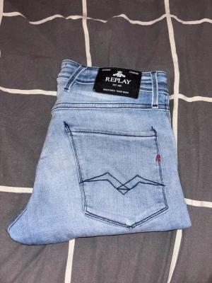 Ljusblå Replay jeans - Säljer ett par ljusblå jeans från Replay med klassisk femficksdesign och snygga detaljer på bakfickan. Jeansen är tillverkade i mjukt denimtyg som ger en avslappnad look. Perfekta till vardagsoutfits!