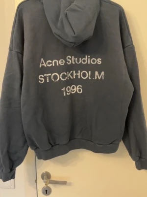 Mörkblå hoodie Acne Studios storlek M - Snygg och stilren hoodie från Acne Studios med klassiskt “Acne Studios Stockholm 1996”-tryck framtill. Mörkblå färg och oversized/avslappnad passform som är perfekt till vardags. Fint skick, säljer då den inte används längre! Storlek M