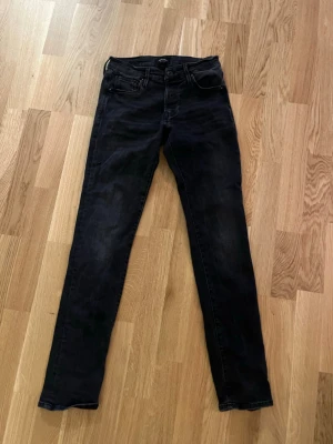 Svarta skinny jeans med hög midja - Snygga svarta skinny jeans med hög midja och klassisk femficksdesign. Jeansen har smal passform hela vägen ner och är tillverkade i stretchigt denimtyg för extra komfort. Perfekta till en avslappnad streetstyle-look. 29/32
