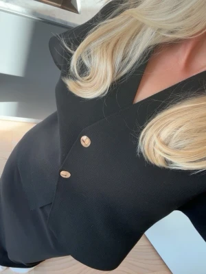 Svart kortärmad blus från Zara - Stilren svart blus med korta ärmar och två dekorativa guldknappar framtill. Sparsamt använd. Storlek M men passar mig som har S i vanliga fall 🩷