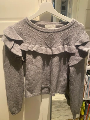 Grå stickad tröja  - Grå stickad tröja från HM med lite söt volang, säljer pga kommer ej till användning längre