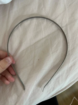 Enkelt metalliskt diadem i silver - Säljer ett minimalistiskt diadem i metall med silverfärg. Diademet har en slät, tunn och rundad form utan dekorationer, perfekt för en clean och stilren look. Passar dig som gillar enkel och modern stil.