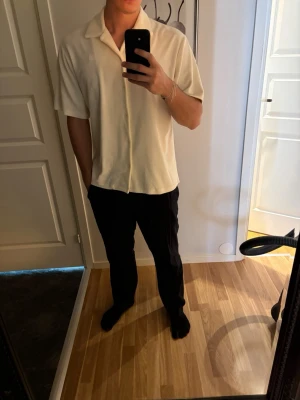 Krämvit kortärmad skjorta med knappar | Jack and Jones Premium - Säljer en krämvit skjorta med korta ärmar och klassisk krage. Skjortan har knäppning framtill och är gjord i ett mjukt material som känns skönt mot huden. Perfekt till sommaren och enkel att styla med olika outfits.