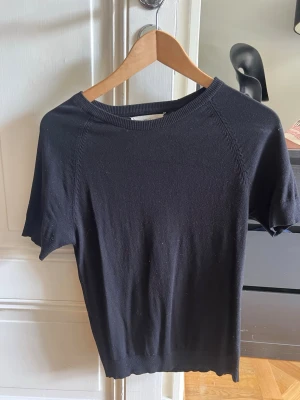Svart kortärmad topp i bomull - En enkel och stilren svart topp med korta ärmar och rund hals. Tillverkad i mjuk bomull som känns skön mot huden. Passar perfekt till jeans eller kjol för en clean look.