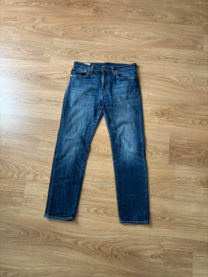 Levi’s 502 - Säljer ett par klassiska mörkblå jeans med raka ben och fem fickor. Jeansen har en snygg tvätt med lätt slitning och kontrastsömmar. Passar perfekt till en avslappnad stil och är tillverkade i denim med bomullskänsla.