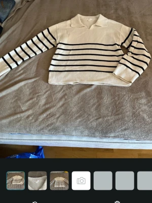 Vit stickad tröja med svarta ränder - Vit stickad tröja från Gina Tricot med svarta horisontella ränder. Tröjan har en klassisk krage, långa ärmar och ribbade muddar vid ärmslut och nederkant. Perfekt för en avslappnad och trendig look.