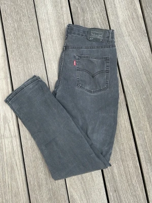Grå Levi's jeans med rak passform - Snygga grå jeans från Levi's med klassisk femficksmodell och rak passform. Jeansen har en diskret tvättad look och Levi's ikoniska röda etikett på bakfickan. Tillverkade i mjukt denimtyg som ger en skön känsla och passar till många olika stilar.