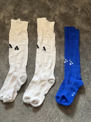 Långa sportstrumpor i vitt och blått - Alla strumpor är i mycket fint skick, aldrig använda. Kan säljas separat vid efterfrågan. Vita Addidas är size 4 medan blåa Craft är size 3/strl 40-42. Strumporna är långa och passar perfekt till sport eller träning. Tillverkade i ett stretchigt material som sitter skönt på benet.
