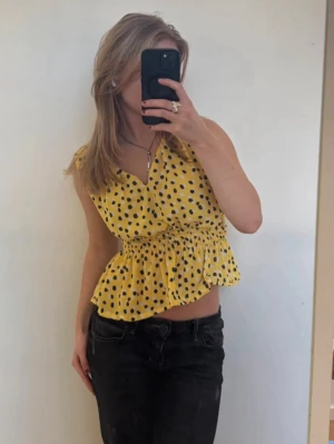 Gul prickig omlottopp med volang - Säljer den snyggaste toppen i gult prickigt tyg! 💗Den är figursydd med smock i midjan och är lite asymmetrisk. Är omsydd av mig. Är i fint skick! Ställ gärna frågor och kika gärna på mina andra artiklar jag säljer!💗💕