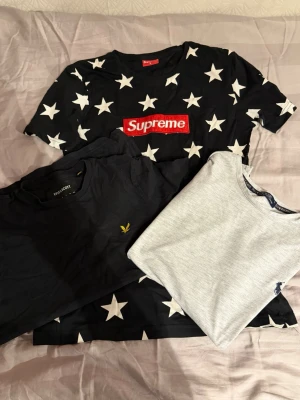 Tre trendiga t-shirts från kända märken - Säljer tre snygga t-shirts: en svart Supreme med vita stjärnor och röd logga, en enkel svart Lyle & Scott med gul logga på bröstet samt en ljusgrå Ralph Lauren med liten marinblå logga. Perfekta för dig som gillar streetwear och klassiska märken.