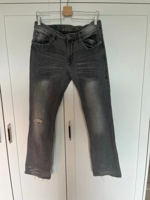 Bootcut Jeans - Säljer ett par vintage grå jeans i bootcut. Jeansen har fem fickor, tydliga tvätteffekter och en avslappnad look. Perfekta för dig som gillar slim fit jeans men som fortfarande faller över skorna snyggt! Liknar Nudiemodellerna Average Joe och Regular Alf.