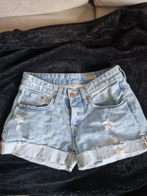 Ljusblå boyfriend jeansshorts - Jeansshorts med slitna detaljer och uppvikta benslut