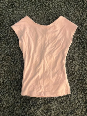 Ljusrosa ärmlös topp med öppen rygg - Söt ljusrosa topp i mjukt material med ärmlös och öppen rygg design och enkel, figurnära passform. Perfekt att styla med jeans eller kjol för en trendig look. 