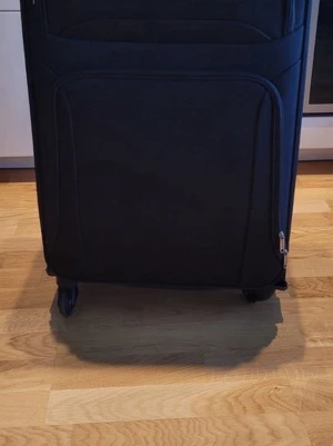 Svart mjuk resväska på hjul - Snygg svart resväska med mjukt tyg, fyra hjul och dragkedja. Väskan har ett stort huvudfack och flera mindre fack på insidan för smart packning. Perfekt för dig som vill resa smidigt och ha koll på dina grejer.
