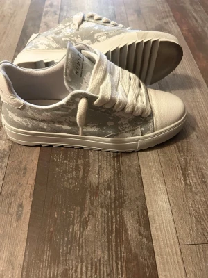 Numeris st45 - Helt nya. Använt bara 5 gånger.Snygga sneakers från Numeris i vitt och ljusgrått med coolt mönster på sidan. Skorna har breda vita skosnören, räfflad sula och är tillverkade i en mix av textil och syntetmaterial. Perfekta för dig som gillar en modern och unik stil.