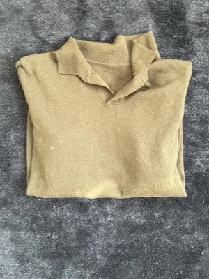 Olivgrön kachmir tröja med krage - Snygg olivgrön kachmire tröja med klassisk krage och långa ärmar. Tröjan har en enkel och stilren design utan synliga loggor eller mönster. Materialet ser ut att vara mjukt och bekvämt, perfekt för lager på lager under kyligare dagar.