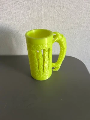Monster hållare med drakhandtag  - Unik neongul mugg med drakskinnsmönster och handtag format som en draksvans. Tillverkad i plast och har detaljerade fjäll över hela ytan. Perfekt för dig som gillar fantasy och vill ha något annorlunda till drycken.