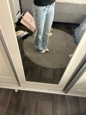 Ljusblå bootcut jeans med låg midja - Ljusblåa jeans med utsvängd passform och låg midja. Jeansen har klassisk femficksdesign och är tillverkade i denim med två olika färger på tyg och en snygg tvätt. Perfekta för en avslappnad och trendig look. Dem är som nya förutom att det är små defekter längst ner på byxan i bak, det är bara att det har rivits upp lite och är endast ett fåtal trådar vilket även kan bli en snygg detalj. Jag är 165 cm lång. 