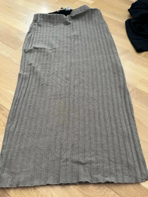 Ribbad beige långkjol från Kappahl - Säljer en ribbad beige långkjol från Kappahl i storlek M. Kjolen har en mjuk och stretchig känsla, rak passform och enkel design som gör den lätt att matcha med olika toppar. Perfekt för dig som gillar stilrena plagg med lite struktur.