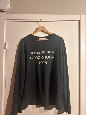 Svart långärmad t-shirt Acne Studios - Svart långärmad t-shirt från Acne Studios med tryck i vitt framtill där det står 'Acne Studios STOCKHOLM 1996” storlek xs men passar 180