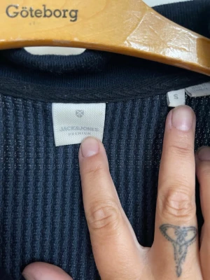 Mörkblå ribbad topp från Jack & Jones - Säljer en mörkblå ribbad topp från Jack & Jones. Toppen har korta ärmar, krage och v-ringning. Samt en likadan fast beige färg i ett pack
