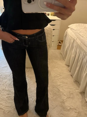 Mörkblå bootcut jeans med vita sömmar - Snygga mörkblå jeans med bootcut-modell och vita kontrastsömmar. Jeansen har låg midja och klassisk femficksdesign. Perfekta för dig som gillar en tidlös och trendig look. 
