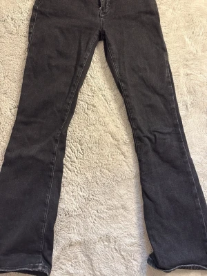 Svarta low flare jeans, längd 31 - Säljer ett par svarta low flare jeans med längd 31 och låg midja. Jeansen har klassisk femficksdesign, dragkedja och knapp i silverfärg. Perfekta för dig som gillar en retroinspirerad look med utsvängda ben.