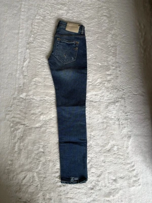 Blå Dondup jeans - Säljer mina blå Dondup jeans i storleken 28. Byxorna har schyssta slitningar och är i mycket bra skick. Säljer då de är för små.