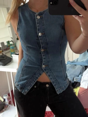 Ärmlös jeanslinnetopp med knappar - Säljer en snygg ärmlös jeanslinnetopp i blå denim.