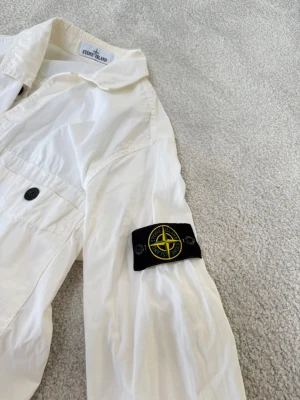 Stone Island jacka  - Säljer denna snygga vita stone island tröja. Jacka som går att använda både på sommaren och vintern, en overshirt. Finns QR kod som visar att den är äkta. Jackan är i fint skick. Storlek S men passar även M. 