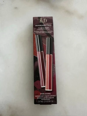 KVD Hyperlight Duo läppstiftset. Långvarig - KVD Hyperlight Duo är ett set med två flytande läppstift i färgerna Queen of Poisons (mörkröd) och Moth Orchid (mauve/rosa). Läppstiften är ultralätta, har matt finish och kommer i smidig tub med svart lock. Perfekt för dig som gillar intensiva färger och lång hållbarhet.