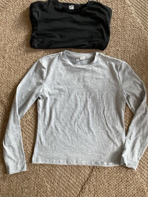 En svart och en grå långärmad topp från SHEIN - Två basic grå och svart långärmad topp från SHEIN i mjukt material. Enkel och clean design med rund halsringning, perfekt att matcha med allt. Passformen är normal och tyget känns skönt mot huden.