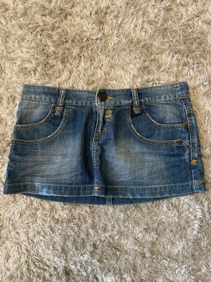Blå lågmidjad jeanskjol med slitningar - Så snygg blå lågmidjad jeanskjol i kort modell med slitna detaljer. Midjemått tvärs över är 40 cm🫶🏼🫶🏼