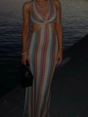 Flerfärgad långklänning med cut-outs - Snygg långklänning med vågigt mönster  som påminner om missoni. Klänningen har halterneck, djup ringning och  cut-outs vid midjan. Använd en gång