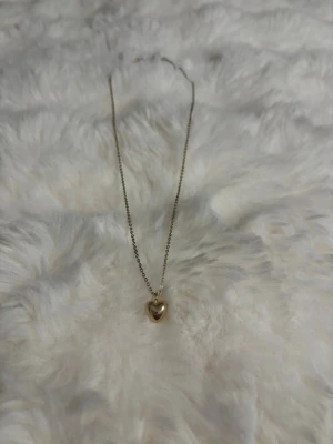 Två guldiga halsband med hängen - Säljer två tunna guldiga halsband. Det ena har ett litet hjärthänge i guldton och det andra har ett ganska basic. Båda halsbanden har enkel, elegant kedja och passar perfekt för att addera en subtil touch till din stil.  Sista bilderna är även tre guldarmband som jag säljer.