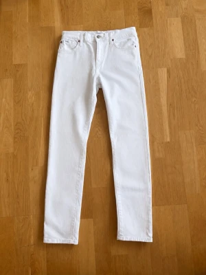 Vita slim jeans från Polo - Säljer ett par vita jeans från Polo med en slim passform och klassisk femficksdesign. Jeansen har metallknappar och nitar samt en liten Polo-logga på fickan. Tillverkade i ett kraftigt bomullstyg som ger en clean och fräsch look.
