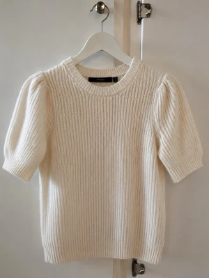 Crémefärgad stickad tröja med puffärm - Säljer en krämvit stickad tröja med korta puffärmar och rund hals. Tröjan har ribbstickad struktur och är gjord i ett mjukt material som känns skönt mot huden. Kan vara något skrynklig då den bara legat i min garderob! 