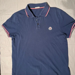 Moncler Maglia Polo - Snygg och exklusiv piké från lyxmärket Moncler. Skicket är 8,5/10, mycket bra och nypris på dessa är 3500 kr men säljer nu för endast 500 kr. Självklart äkta och bevis på detta finns! Hör av er vid funderingar!