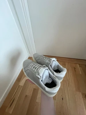 Grå sneakers från Björn Borg - Gråa Björn Borg sneakers i storlek 40  Modellen:  T1620 BSC NUB W LT GREY-WHITE  - Väl använda. Ordinarie kartong medkommer  - Ordinarie pris 1199kr  - Äkta läder