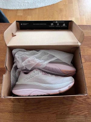 Nya Saucony Hurricane 24 ljusrosa sneakers - Helt nya Saucony Hurricane 24 löparskor för dam, aldrig använda. Säljs i originalkartong.  Modell: Saucony Hurricane 24 Färg: Cloud/Bloom Storlek: EU 38 / US 7 / UK 5 Passform: Medium  Bekväma och stabila löparskor med bra dämpning, passar utmärkt för både löpning och promenader.