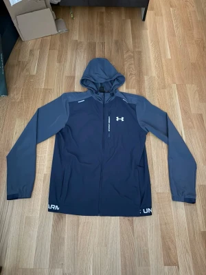 Blå Under Armour Jacka - Snygg blå jacka från Under Armour med dragkedja framtill och huva.