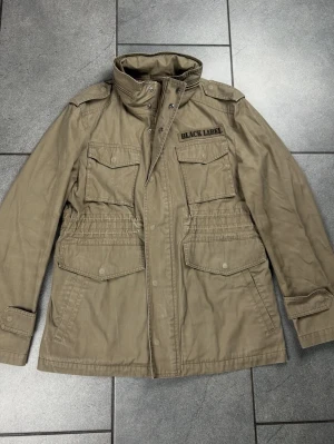 Fieldjacka herr, storlek M - En fieldjacka från ”BLACK LABLE crestbridge” i ett bra skick. Perfekt inför hösten. Storlek L men sitter som en M. 