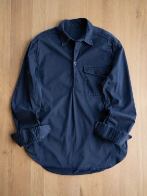 Navy Popover Shirt, size M - Snygg mörkblå  skjorta med lång ärm och klassisk krage. Skjortan har en bröstficka med knapp och knappar vid ärmsluten. Tillverkad i mjuk bomull som känns skön mot huden. Perfekt för dig som gillar en enkel men stilren look.