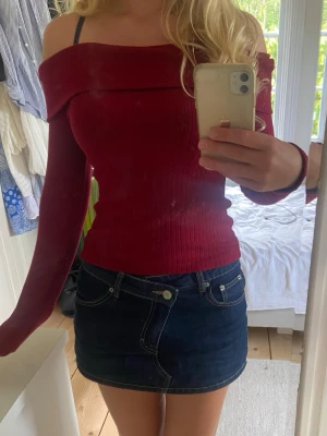 Vinröd offshoulder ribbad topp - Trendig vinröd offshoulder topp med långa ärmar och ribbad struktur. Sitter tight och har en bred krage som vilar över axlarna. Perfekt att styla med kjol eller jeans för en snygg look.