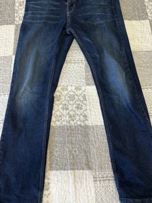 Mörkblå raka jeans från Replay - Säljer ett par mörkblå jeans från Replay med raka ben och klassisk femficksmodell. Jeansen har snygga slitningar och kontrastsömmar. Materialet är bomull med lite stretch för extra komfort. Perfekta till vardagslooken!