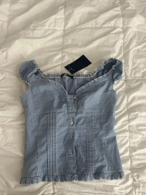 Blåvit rutig topp - Supersöt blåvit rutig blus med små volangdetaljer vid ärmar och urringningen. Perfekt festtopp. Bara använd en gång!💞 