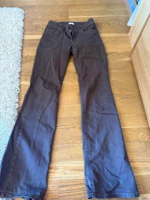 Bruna bootcut jeans - Säljer ett par bruna bootcut jeans med klassisk femficksmodell och normal midja. Jeansen har utsvängda ben och stängs med dragkedja och knapp. Perfekta för dig som gillar retrostil och vill ha ett par sköna jeans i garderoben.