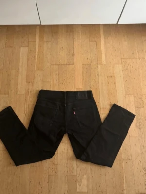 Svarta Levi's 502 jeans - Svarta jeans från Levi's modell 502 med raka ben och klassiska bakfickor. Jeansen har en svart läderpatch i midjan och den ikoniska röda Levi's-taggen på bakfickan. Perfekta för en stilren och avslappnad look.