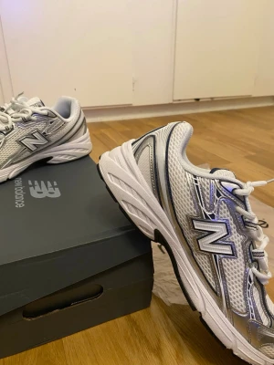 New Balance 740   - Snygga New Balance 740 sneakers i silver och vitt med detaljer i mörkblått. Skorna har en chunky sula och mesh-överdel med syntetiska paneler. Perfekta för dig som gillar retrostil och sportig vibe. Klassisk N-logga på sidan och bekväm passform.