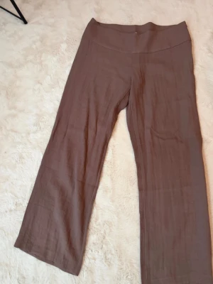 Bruna vida linnebyxor - Säljer ett par bruna linnebyxor med hög midja och raka, vida ben. Byxorna har en enkel och clean look utan synliga fickor eller detaljer. Perfekta för en chill och avslappnad stil. Helt nya utan prislapp 